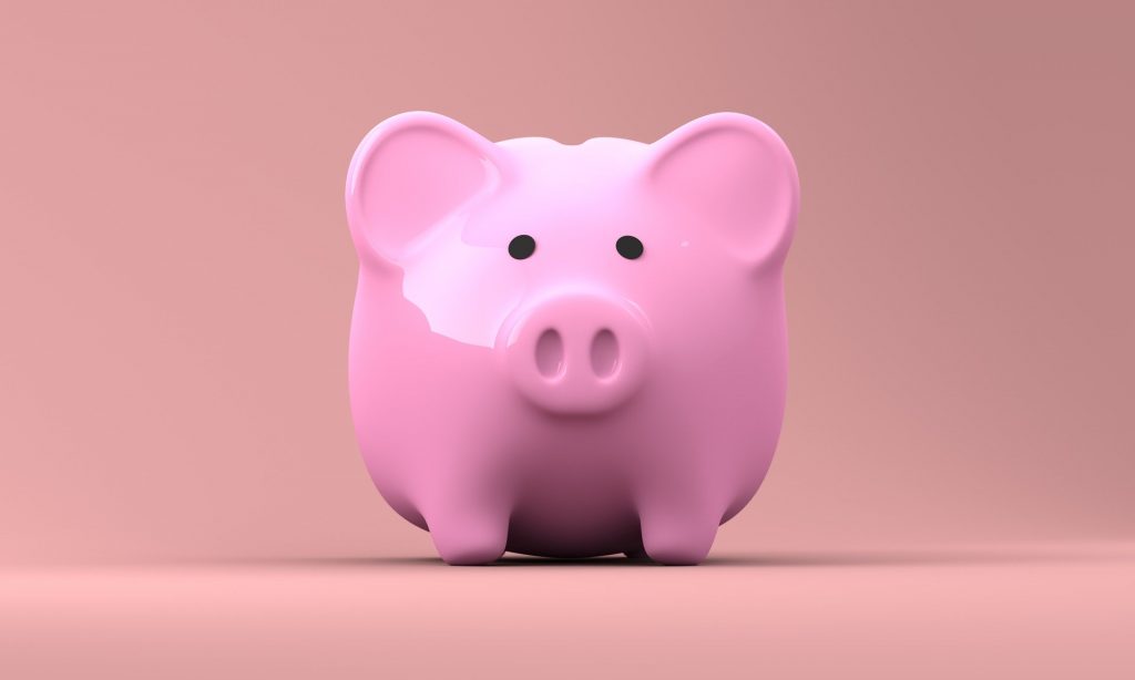 A pink piggy bank on a pink surface, against a pink wall